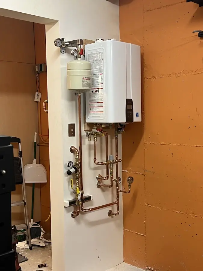 Plumbing technician inspecting water heater connections in Spencer